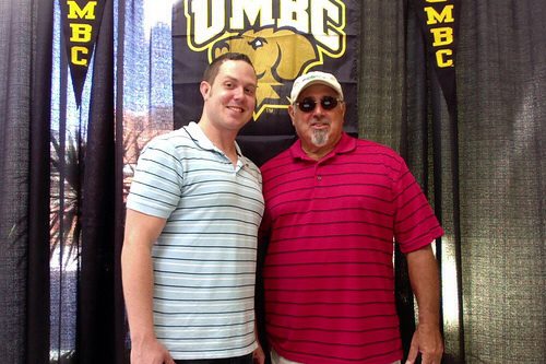 two men in front of a UMBC sign